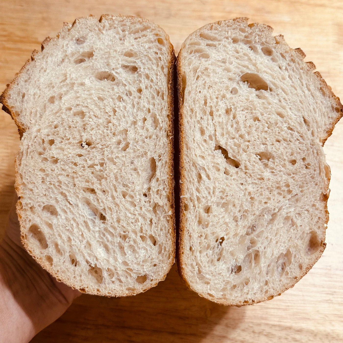 Country sourdough loaf cut in half to reveal its naturally fermented crumb