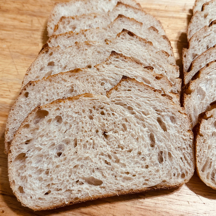 Slices from a naturally leavened country sourdough loaf on a wooden board